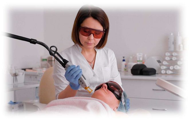косметолог работает аппаратом на лице пациентки
